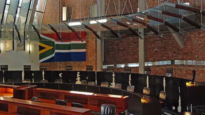 The courtroom of the Constitutional Court in Johannesburg, with the judges' bench in a curve below a large South African flag on a brick wall