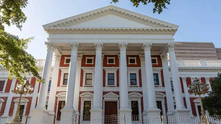 The columned front of the Parliament of South Africa building in Cape Town under a clear sky