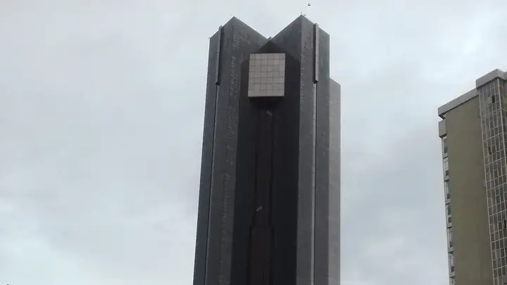 The dark glass tower of the South African Reserve Bank against a cloudy sky in Pretoria