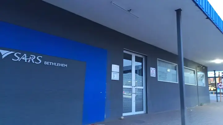 The SARS branch office in Bethlehem, Free State, with the SARS logo on a grey and blue wall beside a glass door